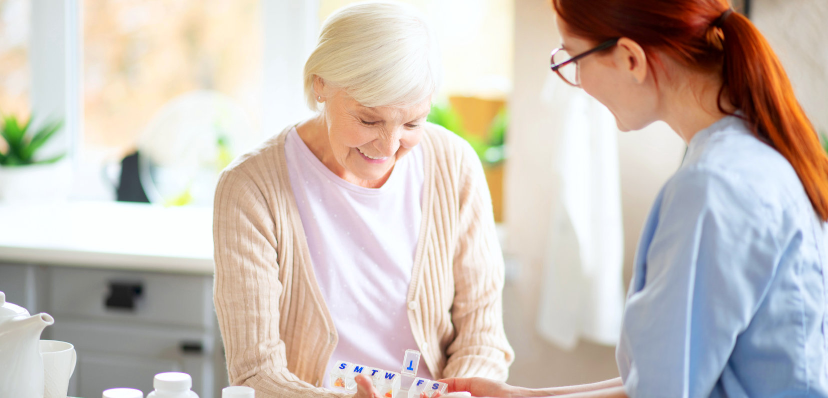 An elderly woman smiling while the nurse is looking at her