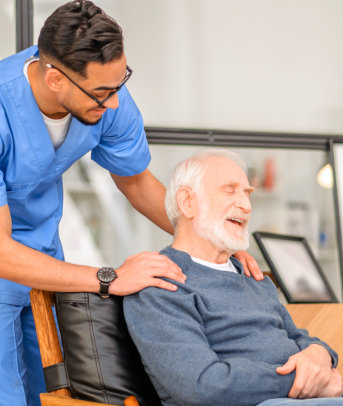 A male nurse holding the shoulder of an elderly man