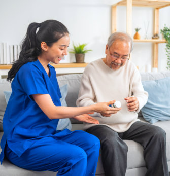 A nurse helping giving a medicine to an elderly man