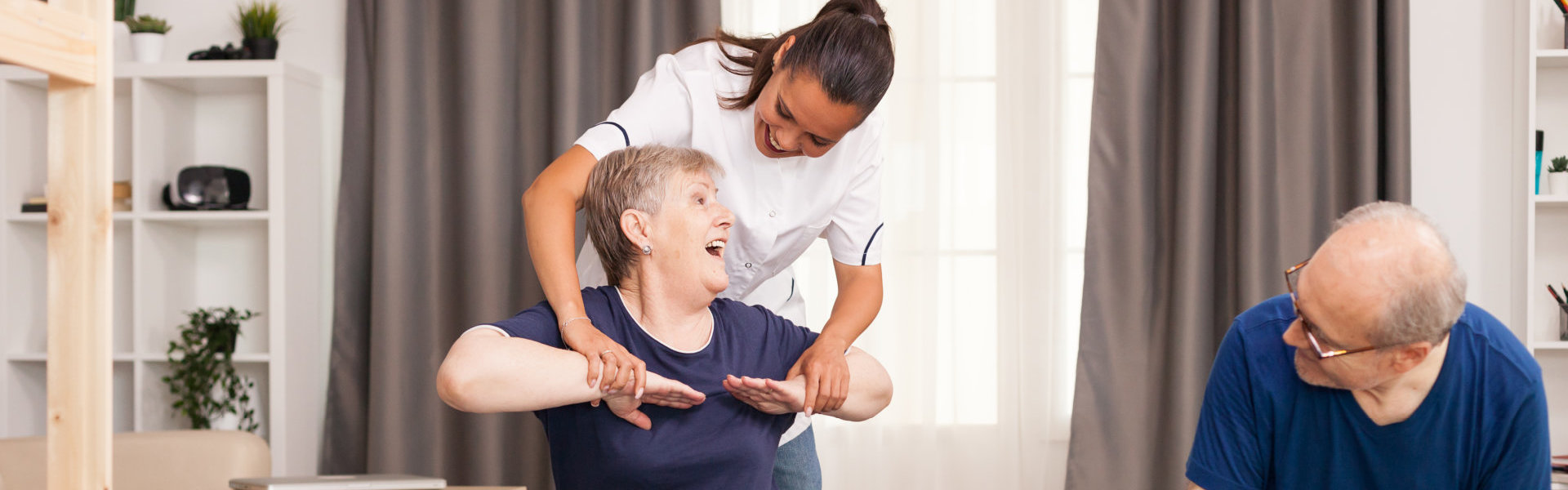 A nurse stretching the elderly woman hand while the elderly man watching