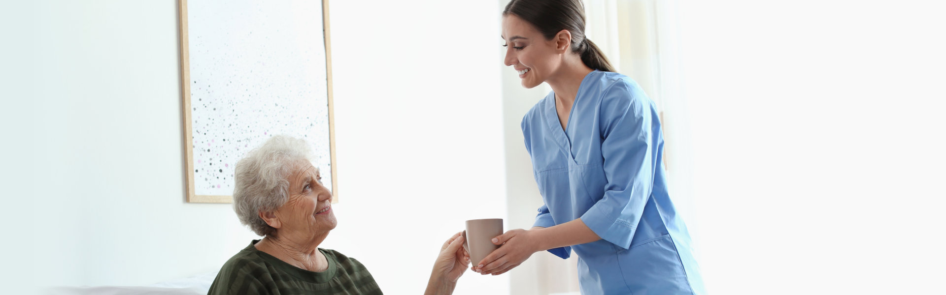 A nurse giving a water to an elderly woman